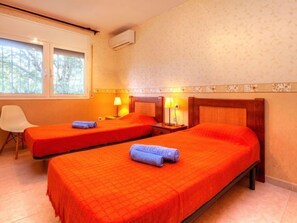 A hotel room with two beds, a chair, and a window.