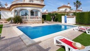 Zona de piscina con piscina, sillas de descanso y un edificio con balcón circular.