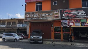 Een motel met een bordje voor 'Changgun Star Motel' en een winkel voor bouwmaterialen genaamd 'Dr. Bajel Hardware' eronder.