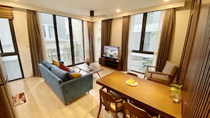 A modern living room with a sofa, dining table, chairs, and a TV. - Apartment Kim Ma (Hanoi)