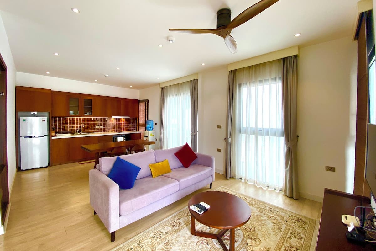 A modern living room with a sofa, a coffee table, and a kitchen in the background.