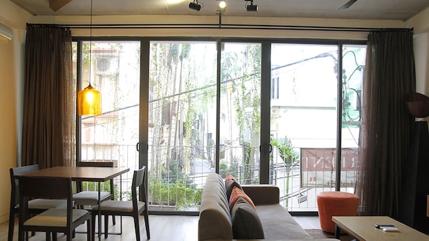 A modern living room with a sofa, a dining table with chairs, and a large sliding glass door leading to an outdoor area. - Apartment Kim Ma (Hanoi)