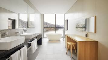 A modern bathroom with a large bathtub, two sinks, and a wooden vanity.