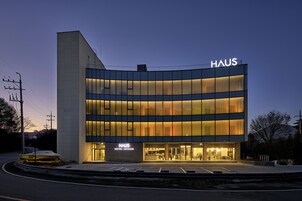 Un hotel moderno con fachada curva, grandes ventanales y un llamativo letrero 'HAUS'.