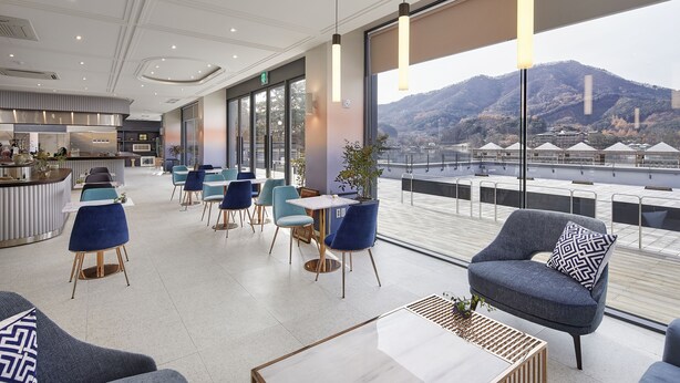 Eine moderne Hotelhalle mit Essbereich, großen Fenstern und Blick auf einen Berg.
