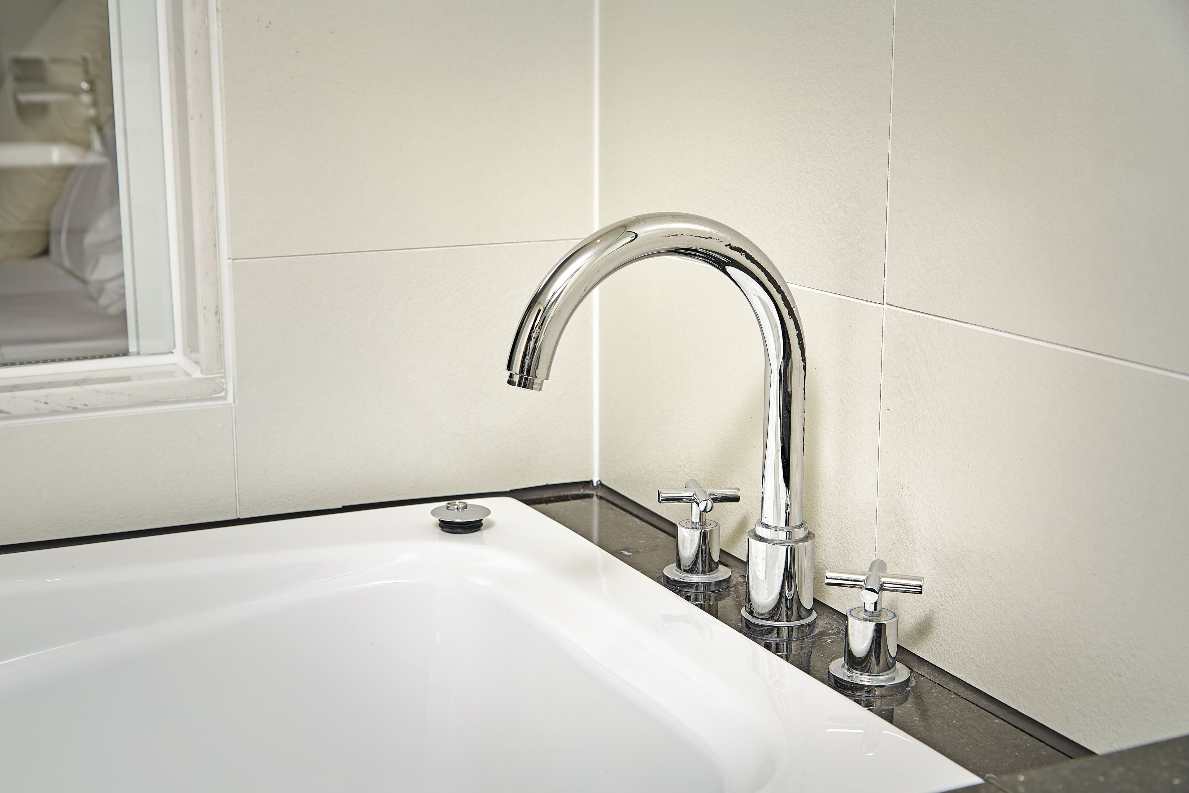Un baño moderno con lavamanos blanco, grifo cromado y espejo.