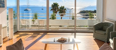 A spacious balcony with a view of the sea and boats, furnished with a sofa, chairs, and a table.