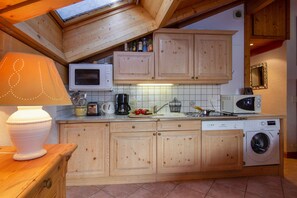 Una cocina con armarios de madera, microondas, lavadora y tragaluz.