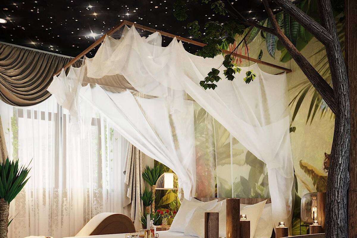 Een slaapkamer met een hemelbed, een ruime stenen wasbak en een muurschildering met tropische motieven.