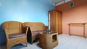 A room with two wicker chairs, a small table with a vase, and a wooden wardrobe. - Samran Residence (Krabi)