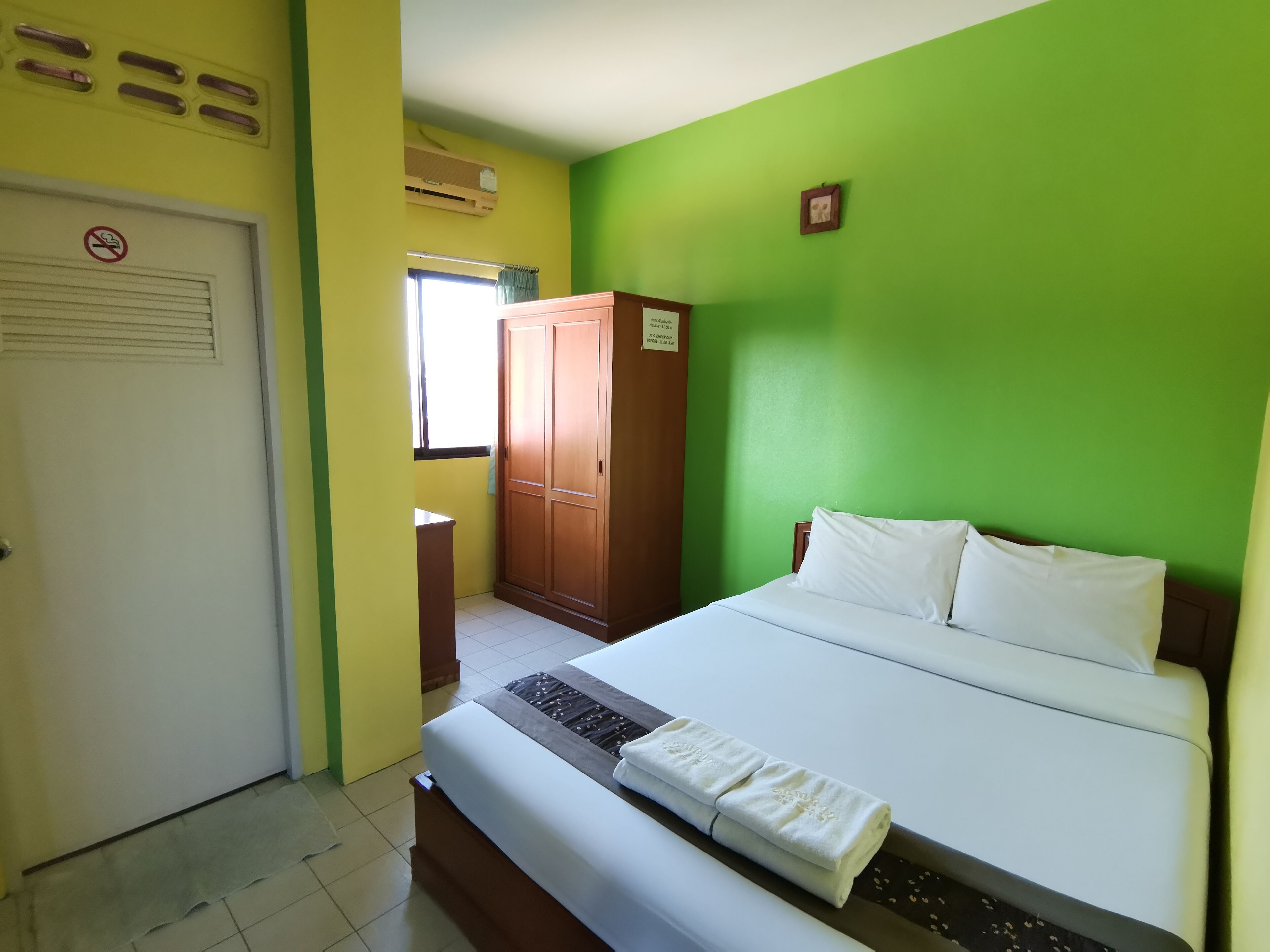 A hotel room with a bed, a wardrobe, a door, and a window.