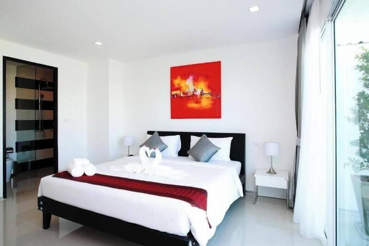 Une chambre d’hôtel moderne avec un grand lit, un tableau au mur et une vue par la fenêtre.