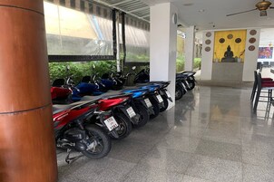 Fileira de motocicletas estacionadas em área interna limpa e bem iluminada, com estátua de Buda e arte decorativa na parede.