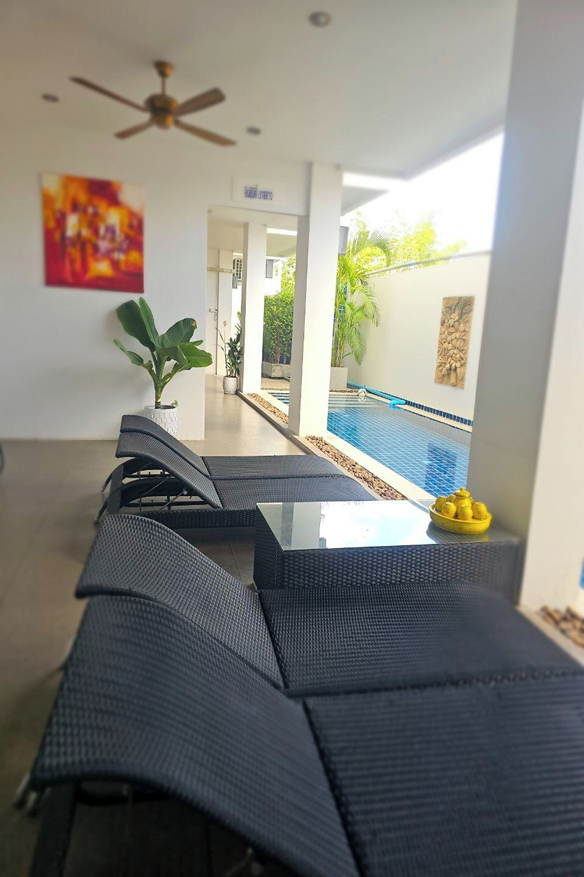 Un área de descanso moderna con vista a la piscina, un ventilador de techo y una planta en maceta.