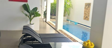 Un área de descanso moderna con vista a la piscina, un ventilador de techo y una planta en maceta.