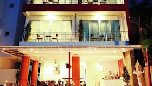 Un hotel de dos pisos con recepción, zona de estar exterior y balcones.