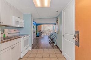 A kitchen with white cabinets, a microwave, and a sink.