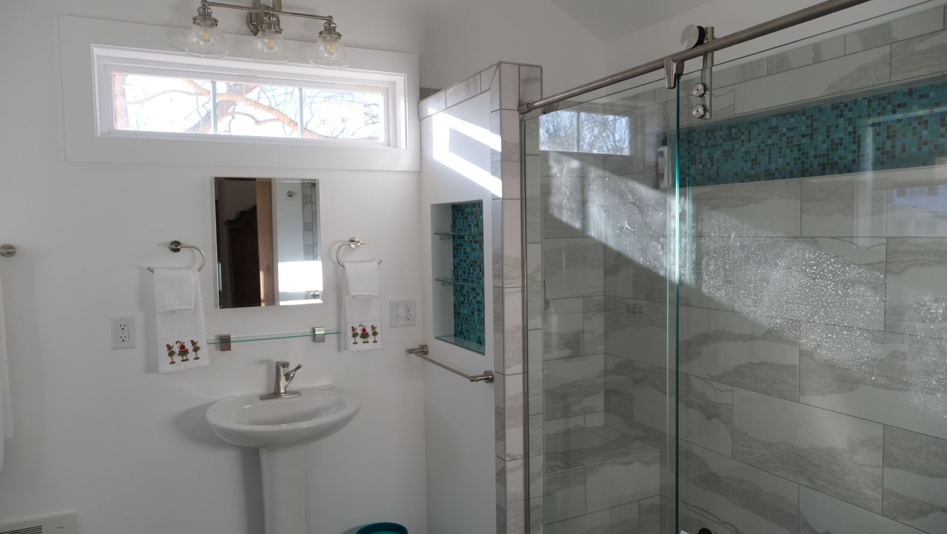 A modern bathroom with a glass shower enclosure, a white sink, and a mirror above it.