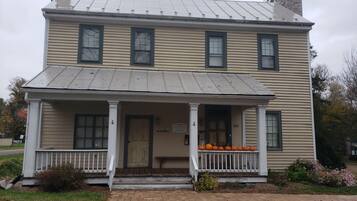 A two-story building with a porch, a chimney, and a sign indicating it is a historic site.