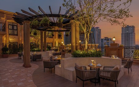 A rooftop terrace with outdoor seating, columns, and hanging plants.