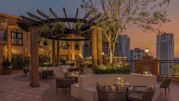 A rooftop terrace with outdoor seating, columns, and hanging plants.