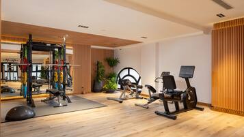 A modern gym with various exercise equipment, including a squat rack, weight bench, and cardio machines.