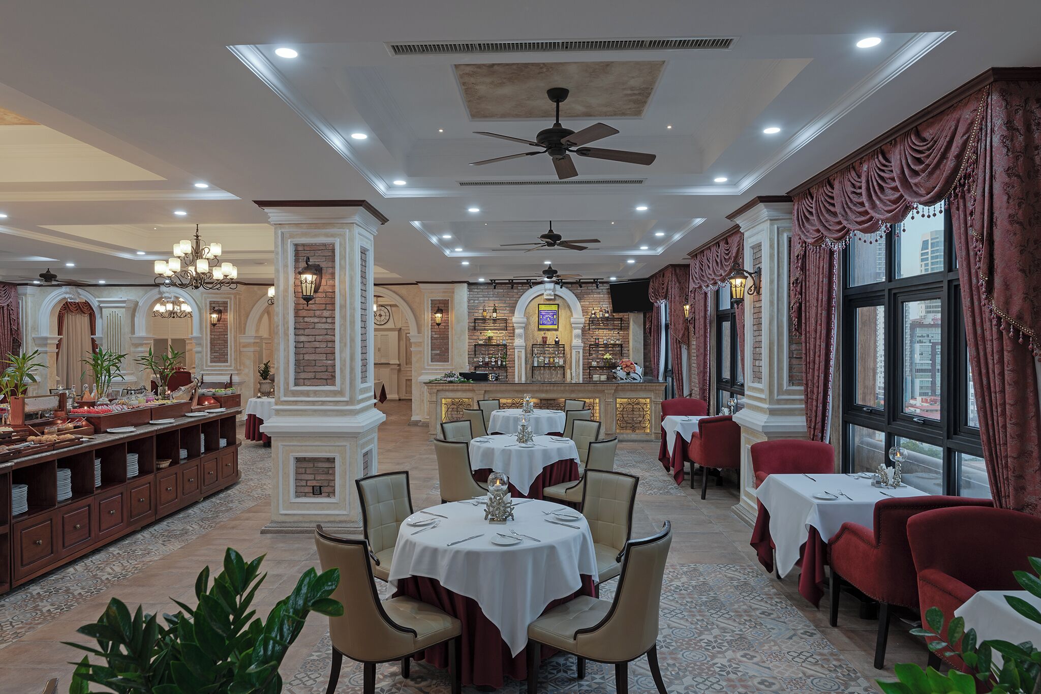 A restaurant with round tables, red chairs, and a bar area in the background.