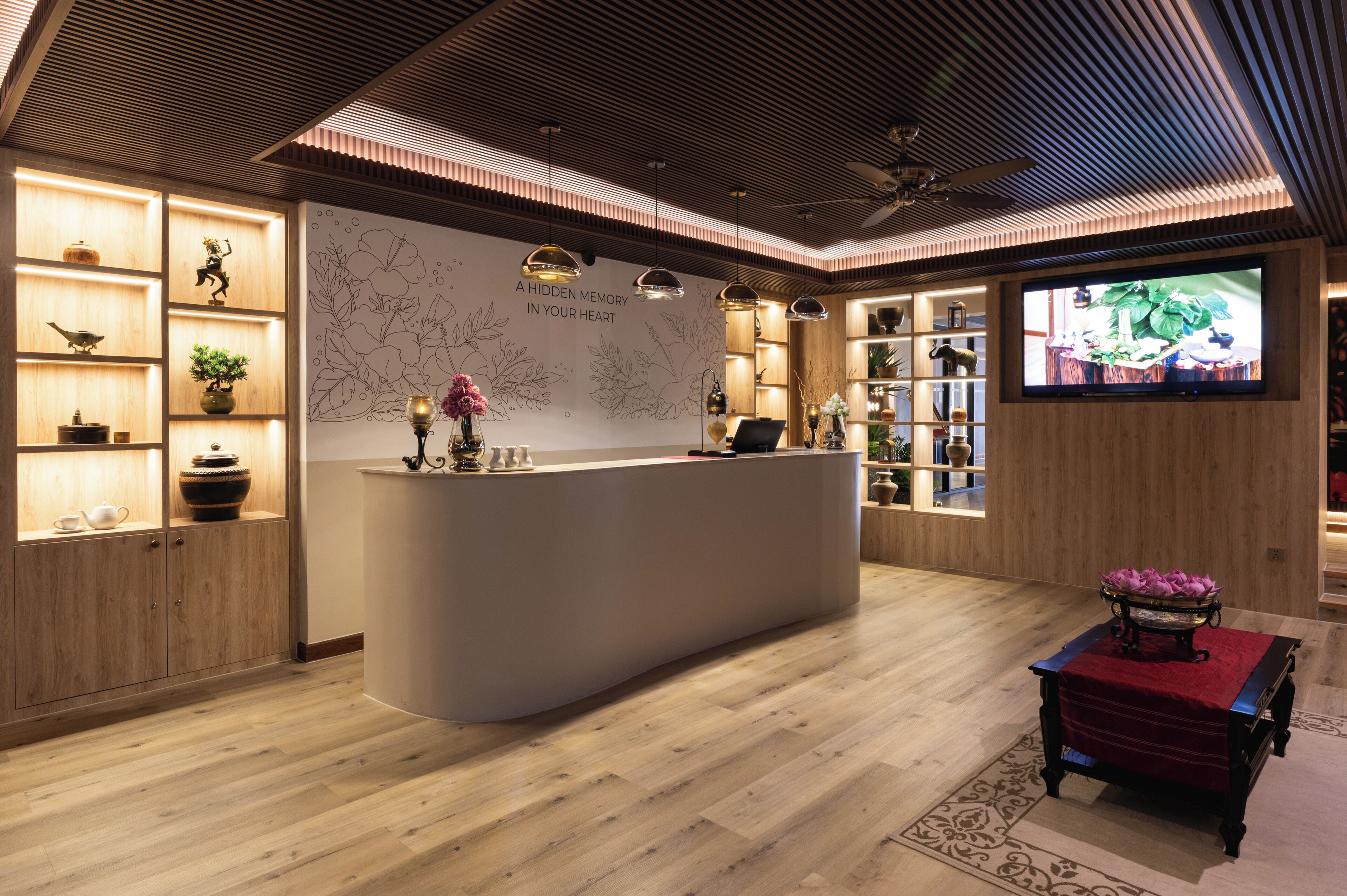 A reception area with a wooden reception desk, a wall with a floral mural, and a television screen displaying a nature scene.