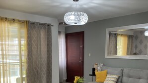 A modern living room with a glass coffee table, a grey sofa, and a black ottoman. - 3 Bedroom Apartment with Resort like Pool (Stgo)