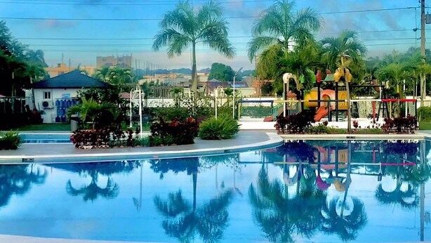 A swimming pool with a playground area, surrounded by palm trees and a clear sky. - 3 Bedroom Apartment with Resort like Pool (Stgo)