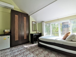 Quarto com cama, escrivaninha, guarda-roupa e uma janela grande.