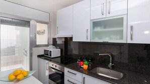 Una cocina moderna con armarios blancos, encimera negra, horno empotrado, microondas, fregadero y ventana con vistas.