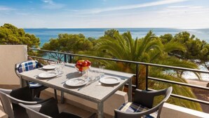 Una mesa para dos con vista al mar y a los árboles.