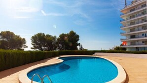 Una piscina de borde curvo, rodeada de una solana con baldosas.