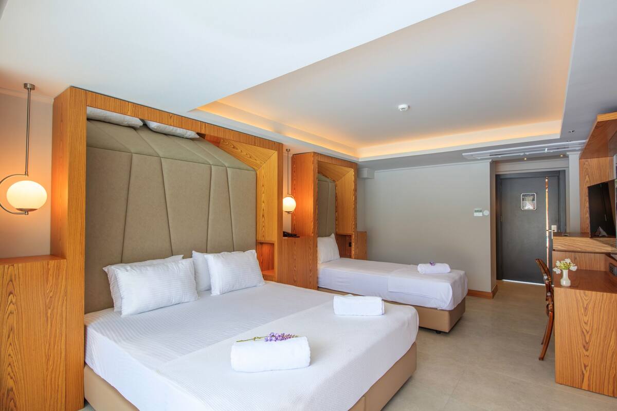 Habitación de hotel con dos camas, cabeceros de madera, un escritorio y una silla.