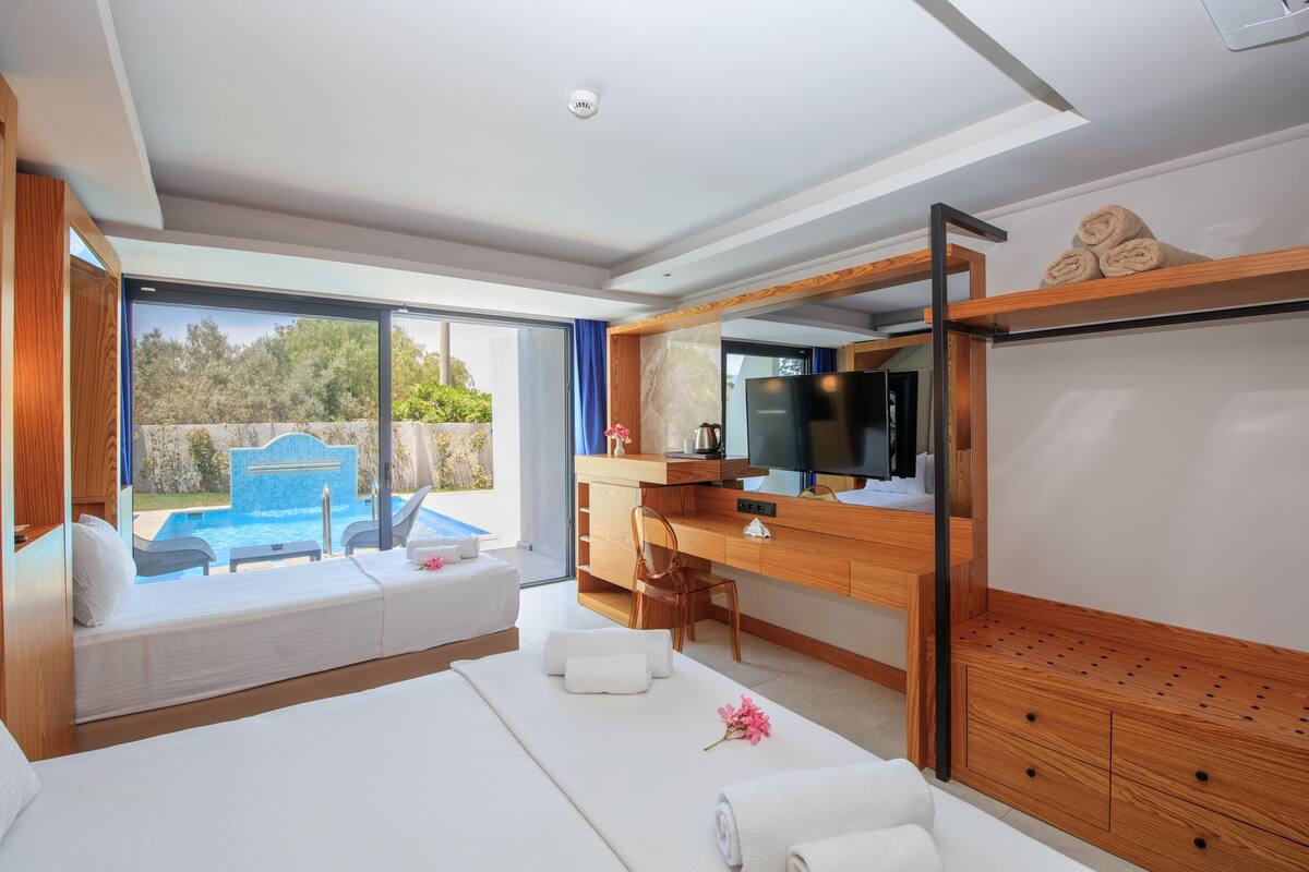 Habitación de hotel moderna con una cama grande, un escritorio, un televisor y vistas a una piscina.