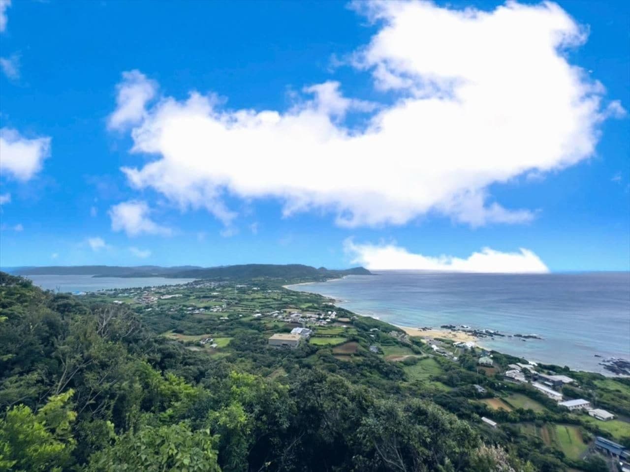 Eine Küstenlandschaft mit blauem Himmel, einem Strand und vereinzelten Gebäuden.