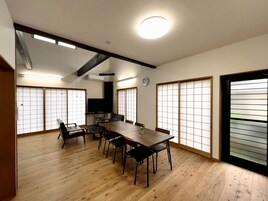 Una habitación tradicional japonesa con suelo de tatami, una mesa baja con sillas, puertas correderas shoji y un candelabro en el techo.
