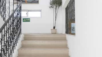 A staircase with beige steps, a black railing, a potted plant, and a framed artwork on the wall.