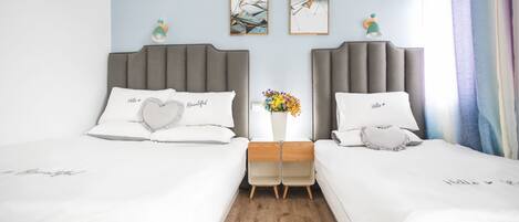 Habitación doble con dos mesitas de noche, un florero y dos cuadros en la pared.