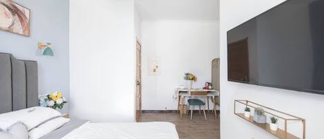 A bedroom with a bed, a desk, and a TV mounted on the wall.
