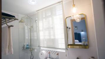 A bathroom with a glass shower enclosure, a toilet, a sink, and a mirror.