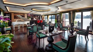 A luxurious dining area with a grand piano, elegant chairs, and a view of the water. - Orchid Premium Cruises (Hai Phong)