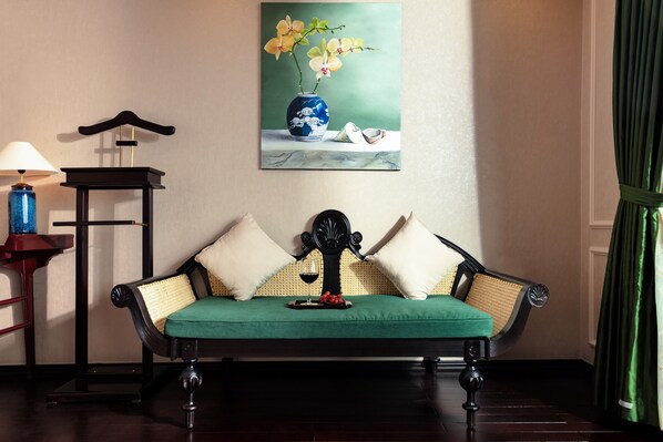 Un canapé traditionnel avec des coussins, une petite table avec une lampe et un tableau représentant des fleurs accroché au mur.