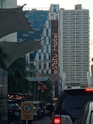 A hotel with a prominent sign, a busy street, and a speed limit sign. - deSatu Hotel (Medan)