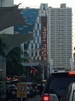 A hotel with a prominent sign, a busy street, and a speed limit sign.