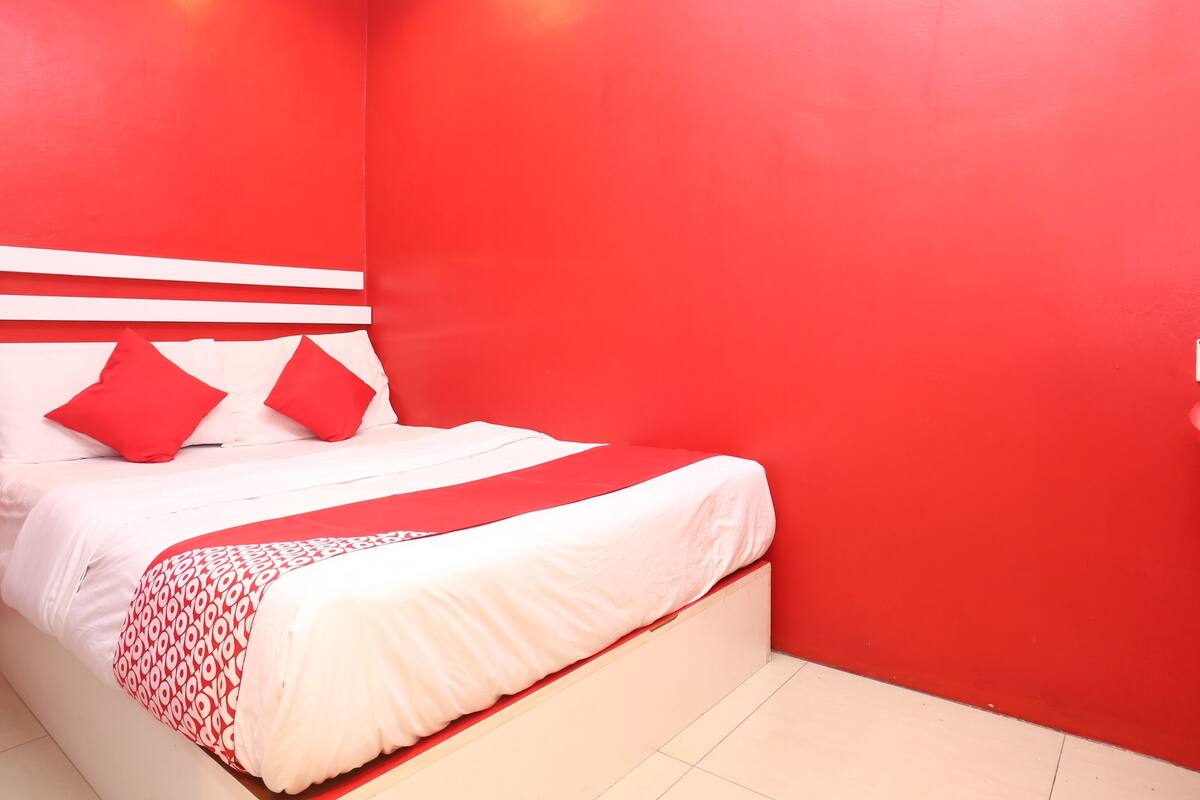 Ein Zimmer mit einem Bett, roten Wänden und einem weißen Kopfteil.