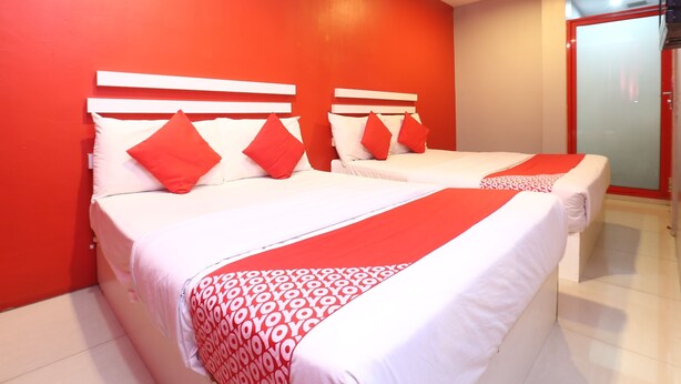 Une chambre d’hôtel avec deux lits, des murs rouges et une couvre-lit rouge et blanche.