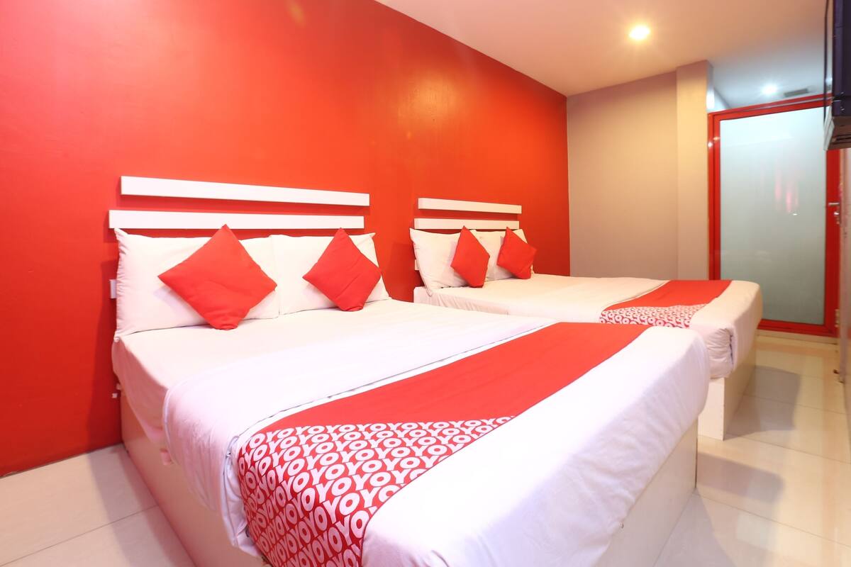 Ein Hotelzimmer mit zwei Betten, roten Wänden und einer roten und weißen Bettdecke.
