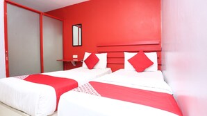 Une chambre d’hôtel avec deux lits, des murs rouges et un miroir au mur.